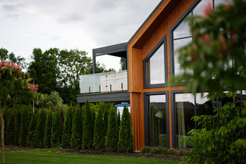 Modern wooden house with large windows surrounded by trees and greenery