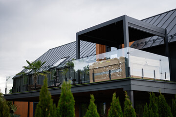 Modern house exterior with spacious balcony and lush green landscaping