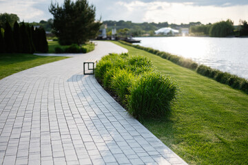 Scenic riverside park path with grass, bench, and tranquil water view