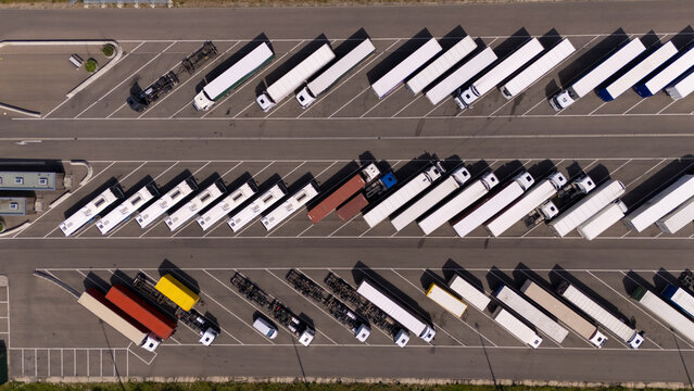A large parking lot with many trucks and buses parked in rows. Aerial view.