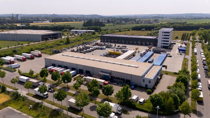 A large warehouse with many trucks parked outside. Aerial view.