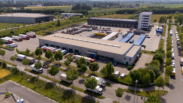A large warehouse with many trucks parked outside. Aerial view.