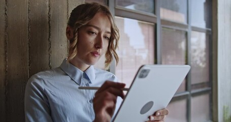 Concentrated young woman engages with her digital tablet and stylus, actively learning and designing. She represents modern education and the use of technology for skill development and creative work.