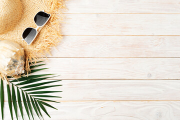 Vacation travel planning simple background of straw hat sunglasses palm leaves and shell on white planks flat lay with copy-space