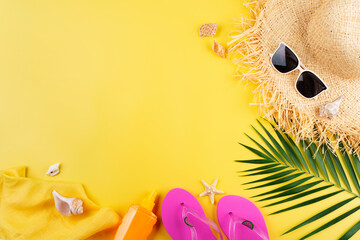 Vacation planning simple theme of straw hat sunglasses flip flops and palm leaves on uniform yellow background flat lay with copy-space