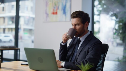 Focused manager looking computer screen workplace closeup. Man making coffee sip