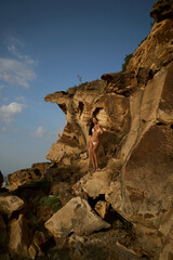 Golden Hour Climb: Woman in Swimsuit Against Rugged Sea Cliffs
