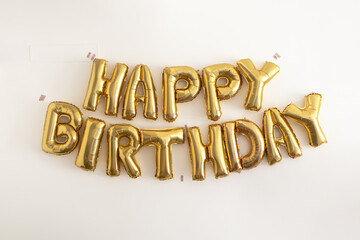 Golden foil Happy Birthday letter balloons on white background, minimalist