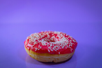 Flat lay of pink donut decorated with sprinkles on blue background