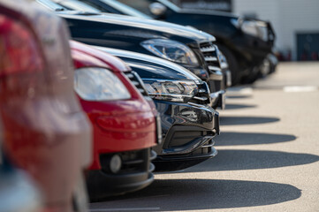 Various cars parked in an organized row at a parking lot during a sunny day