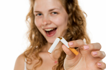 Young woman breaking cigarette in half, smiling confidently. Symbolizing quitting smoking, health...