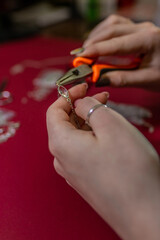 Fototapeta premium Repair of gold jewelry. Hands of the jeweler with tools and jewellery isolated on white background.