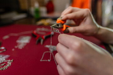 Repair of gold jewelry. Hands of the jeweler with tools and jewellery isolated on white background.
