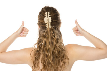 Back view of woman with wavy blonde hair in half-up style using beige claw clip, giving thumbs up...