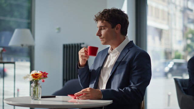 Business owner drinking espresso in city restaurant closeup. Man reading sms