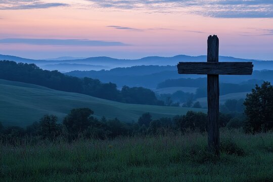 Weathered wooden cross stands against a tranquil dawn sky over rolling hills and misty valleys in a serene landscape, symbolizing peace and reflection