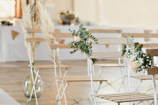 Guest chairs decorated with small bouquets for outdoor wedding ceremony