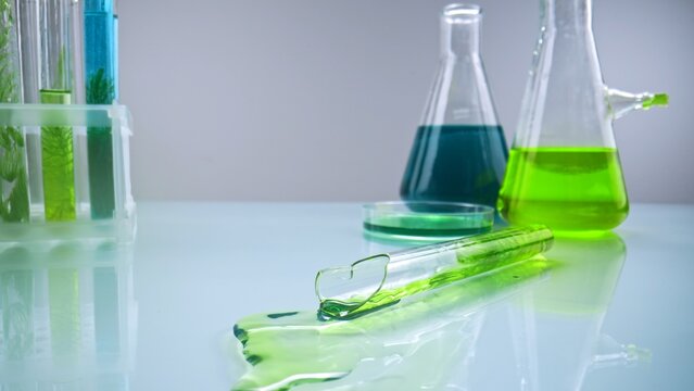 Broken test tube with green chemical spill in laboratory