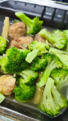 Fried broccoli with sweet and sour gravy in stainless steel tray.