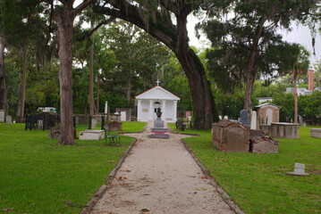 Historical Tolomato Cemetery  in St. Augustine Florida, Detailing its storied history within the historical district surrounded by lush trees and vibrant green foliage.

