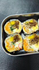 Sushi roll with pork, egg and vegetables on black background. Sushi roll with tuna, egg and vegetables. Japanese food. 