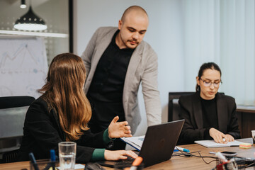Fototapeta premium Professional team members engaged in a discussion at a workplace, sharing ideas and analyzing data together for better project outcomes in a collaborative environment.