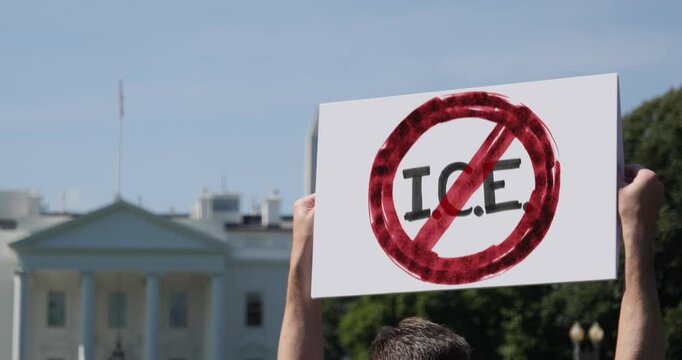 A protester stands outside the White House holding a bold sign with a red strike through &ldquo;I.C.E.,&rdquo; voicing opposition to immigration enforcement policies and advocating for immigrant rights. 14678