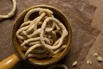 Top view of fried corn rings snack in a brown ceramic bowl, Overhead view of nigerian kokoro egba...