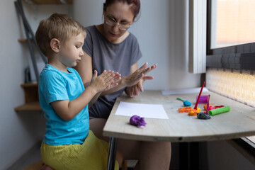 Teacher helping young child playing with modeling clay in art class