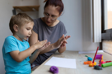 Mother and son clapping hands while playing with modeling clay