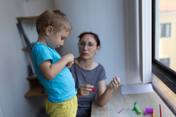 Child playing with modeling clay with teacher at art school