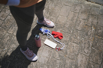 Fitness Gear with Shoes, Jump Rope, Water Bottle, and Smartphone on Outdoor Pavement