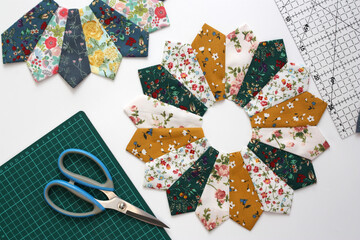 On a white background, fabric blocks for a handmade patchwork quilt. The blocks are called the Dresden Plate. Multi-colored cotton fabrics, scissors . Concept modeling and sewing as a hobby.