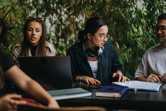 A group of focused students studying together in a cozy coffee shop environment. The scene highlights collaboration, teamwork, and academic pursuits. Ideal for concepts of education and student life.