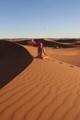 Woman doing yoga pose in the desert dunes