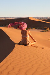 Woman doing yoga pose in the desert dunes