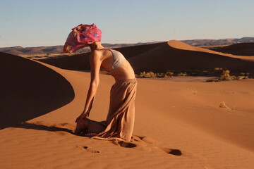 Woman doing yoga pose in the desert dunes