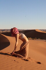 Woman doing yoga pose in the desert dunes