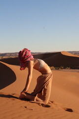 Woman doing yoga pose in the desert dunes