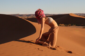 Woman doing yoga pose in the desert dunes