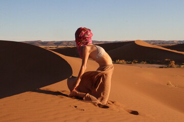 Woman doing yoga pose in the desert dunes