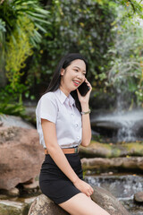 A female student is talking on the phone with a bright smile on her face.