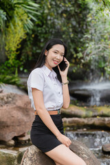 A female student is talking on the phone and smiling happily about her studies.