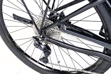 Studio shot of a bike's rear cassette and derailleur in close-up, details of the chain, spokes, and gears.