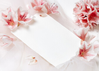 Blank vertical paper card near pink azalea flowers closeup, spring wedding mockup