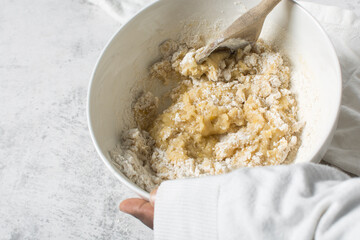 mixing flour into vanilla cookie dough in a white mixing bowl, plain vanilla cookie dough about to be baked, process of making vanilla cookie dough