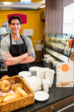 Wicker basket is holding assorted bagels and rolls beside pastry display in yellow caf&eacute; interior