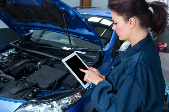 Blue sedan hood remaining open in repair garage, tablet displaying live engine data near tool chest