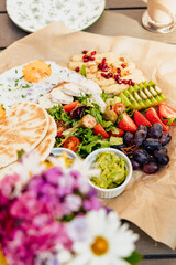 Breakfast on the summer terrace of a cafe in a European city, emotions, eggs, croissant, sauce, salad, flowers, atmosphere