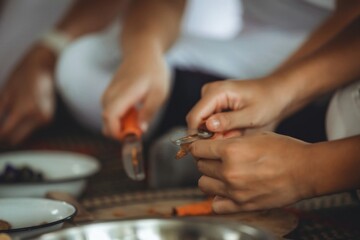 Close-up of hands peeling vegetables during traditional cooking preparation